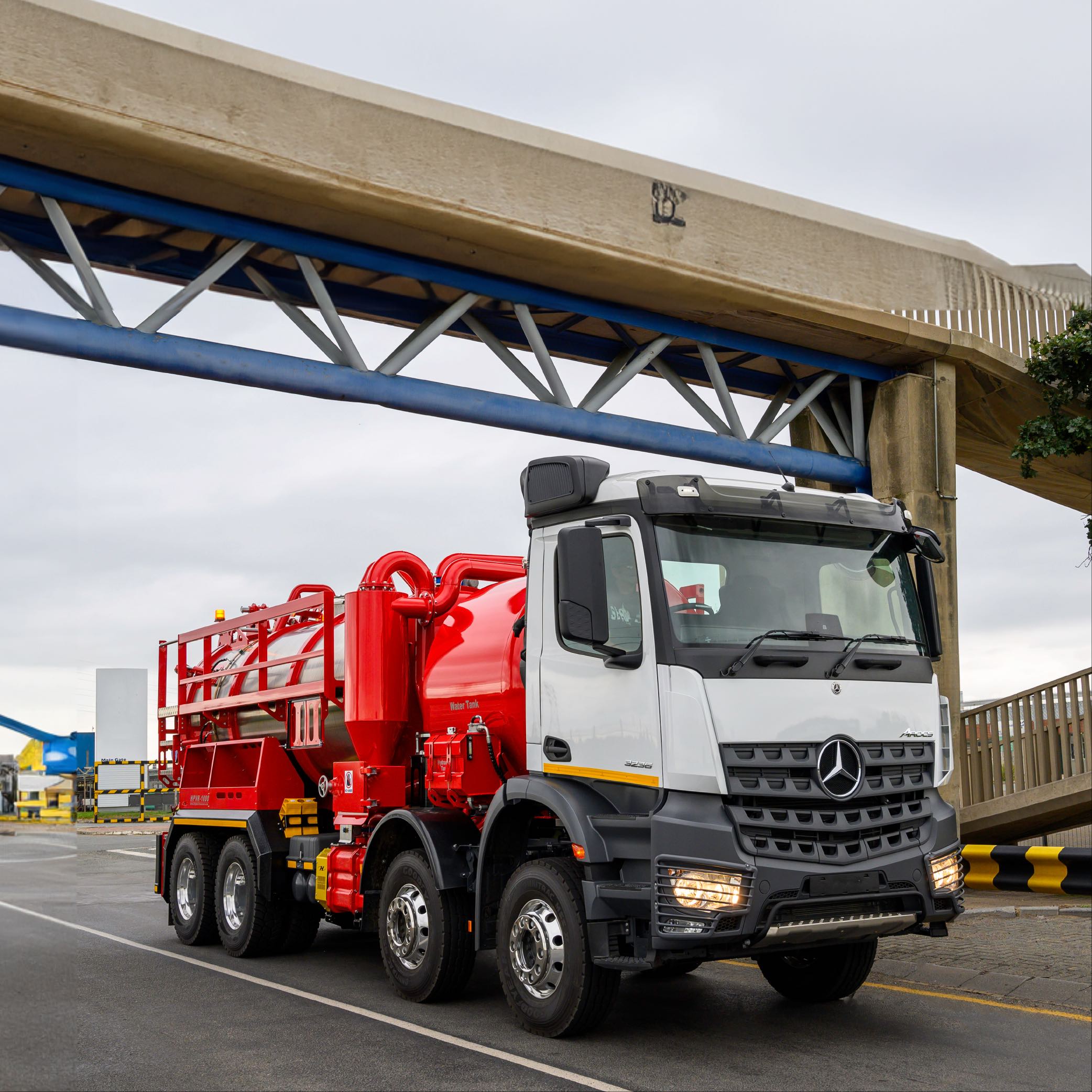 Red industrial vacuum truck for dangerous waste by Highpoint Manufacturing also known as Highpoint Vacuum and Highpoint Group, driving out of a refinery plant